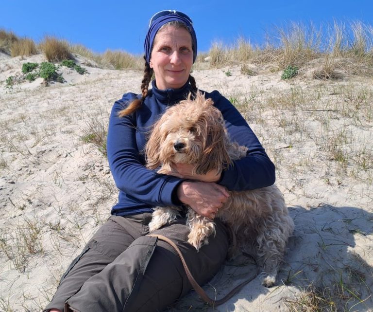Nordseedünen mit blauem Himmel. Corinna sitzt mit Emmy in den Dünen.